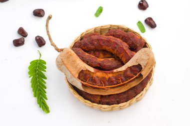 Tamarind _ fasülyesi tohumlarla dolu tohumlar gibi arkaplandaki lifli bir hamurla çevrili kabuklu demirhindi sepetini doldurup beyaz dokuya yerleştirilmiş.
