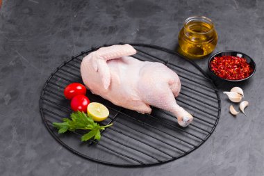 Izgarada pişirilmiş çiğ tavuk kısmen küçük domates, sarımsak, kırmızı biber, yağ ve limon dilimleri ile süslenmiş taş desenli ya da grafit renkli arkaplanlı servis kutuları, izole edilmiş