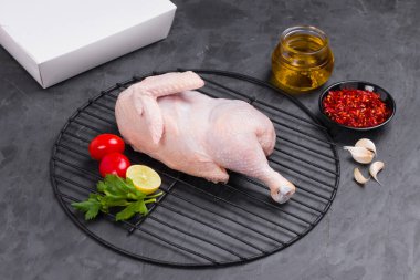 Izgarada pişirilmiş çiğ tavuk kısmen küçük domates, sarımsak, kırmızı biber, yağ ve limon dilimleri ile süslenmiş taş desenli ya da grafit renkli arkaplanlı servis kutuları, izole edilmiş