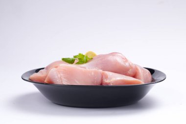 Çiğ tavuk biryani derisiz kesilmiş siyah kabın üzerine yerleştirilmiş ve kişniş yaprağı ile süslenmiş.