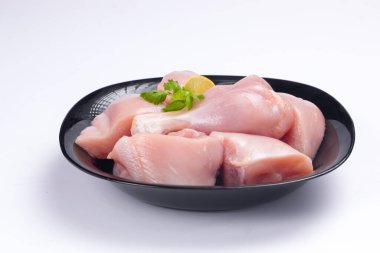 Çiğ tavuk biryani derisiz kesilmiş siyah kabın üzerine yerleştirilmiş ve kişniş yaprağı ile süslenmiş.