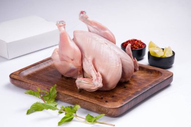 Tahtaya konmuş taze çiğ tavuk ve nane yaprağı ile süslenmiş küçük kaseler ve beyaz dokulu limon dilimleri.