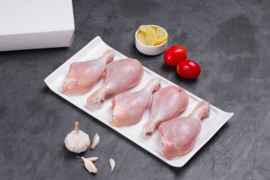 Domates, limon dilimleri ve gri arka planda sarımsaklı tavuk budu.