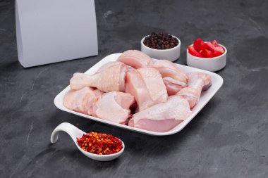Çiğ köri soslu tavuk derisi beyaz tabağa dizilmiş ve karabiber ve domates dilimleri ile süslenmiş. 