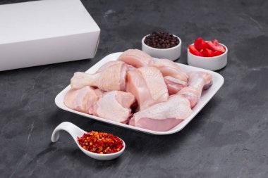 Çiğ köri soslu tavuk derisi beyaz tabağa dizilmiş ve karabiber ve domates dilimleri ile süslenmiş. 