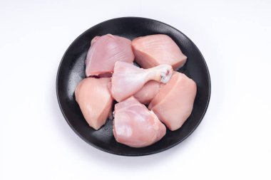 Çiğ tavuk derisiz köri, beyaz desenli arka planda siyah tabakta sıralanmış.