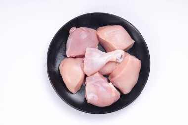 Çiğ tavuk derisiz köri, beyaz desenli arka planda siyah tabakta sıralanmış.