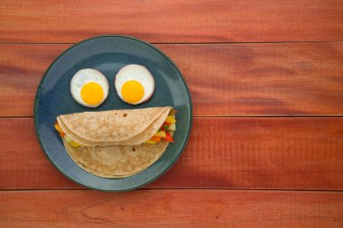 Chappati, buğday unundan yapılmış sağlıklı yiyecekler ve sebzelerle doldurulmuş ve gözler kaynamış yumurtalardan yapılmış ve mavi desenli seramik tabakta servis ediliyor..