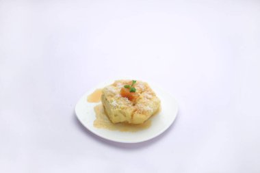 Ananas sufle, tatlı sufle beyaz yuvarlak tabaktaki beyaz dokuya sosla servis edilir.