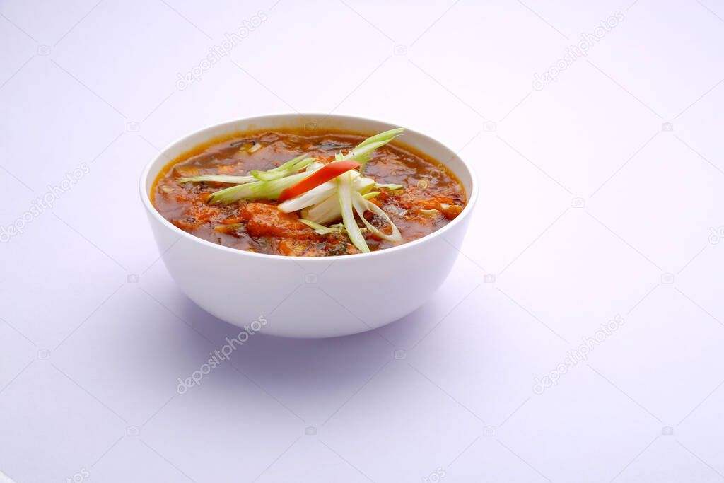 Chicken Manchurian soup ,garnished with vegetables arranged in a white bowl with white texture or background