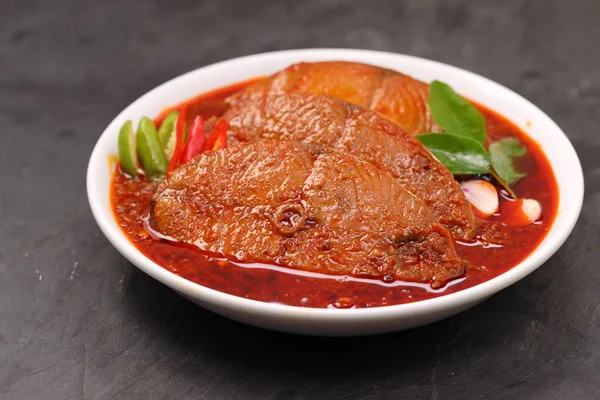 Kahin Balık köri, geleneksel Hint balığı körisi, köri yapraklarıyla süslenmiş beyaz bir seramik kasede düzenlenmiş, arpacık soğuğu ve gri dokulu arka planda taze soğuk, izole edilmiş..