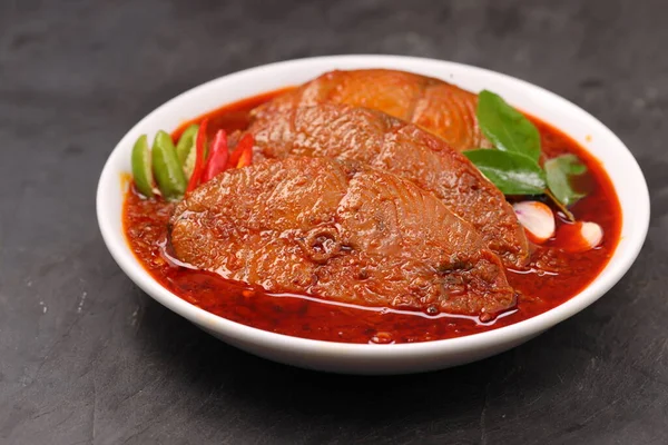 Kahin Balık köri, geleneksel Hint balığı körisi, köri yapraklarıyla süslenmiş beyaz bir seramik kasede düzenlenmiş, arpacık soğuğu ve gri dokulu arka planda taze soğuk, izole edilmiş..