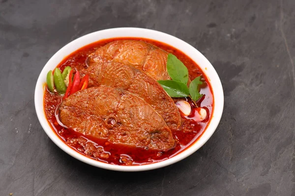 Kahin Balık köri, geleneksel Hint balığı körisi, köri yapraklarıyla süslenmiş beyaz bir seramik kasede düzenlenmiş, arpacık soğuğu ve gri dokulu arka planda taze soğuk, izole edilmiş..