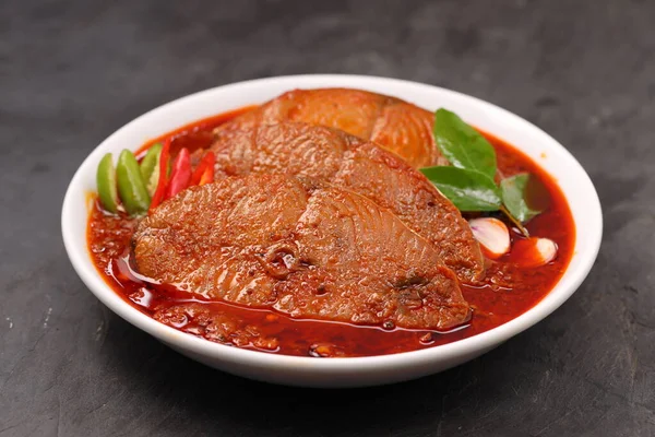 Kahin Balık köri, geleneksel Hint balığı körisi, köri yapraklarıyla süslenmiş beyaz bir seramik kasede düzenlenmiş, arpacık soğuğu ve gri dokulu arka planda taze soğuk, izole edilmiş..