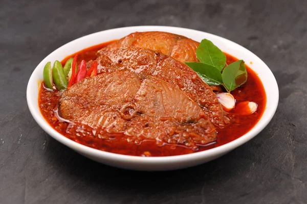 Kahin Balık köri, geleneksel Hint balığı körisi, köri yapraklarıyla süslenmiş beyaz bir seramik kasede düzenlenmiş, arpacık soğuğu ve gri dokulu arka planda taze soğuk, izole edilmiş..