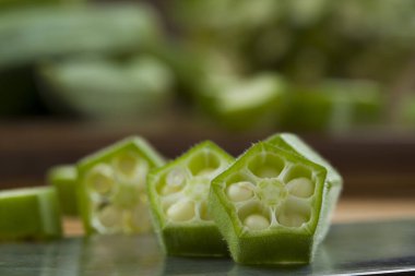  Bamya ya ya da Lady 'nin parmağı ya da Bhindi. Taze yeşil sebze dilimlenmiş halkaların yakın plan görüntüsü. Arkasına bamya yerleştirilmiş, seçici odaklı.