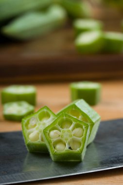  Bamya ya ya da Lady 'nin parmağı ya da Bhindi. Taze yeşil sebze dilimlenmiş halkaların yakın plan görüntüsü. Arkasına bamya yerleştirilmiş, seçici odaklı.