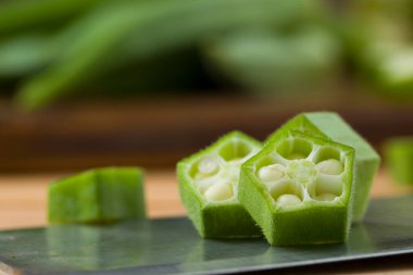  Bamya ya ya da Lady 'nin parmağı ya da Bhindi. Taze yeşil sebze dilimlenmiş halkaların yakın plan görüntüsü. Arkasına bamya yerleştirilmiş, seçici odaklı.