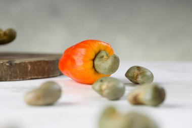 Arkasında kaju fıstığı ya da kaju çekirdeği olan beyaz bir arka planda, seçici bir odak noktası olan kaju elması.