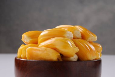 Olgun Jackfruit, beyaz desenli arka planlı ahşap bir kasede güzelce düzenlenmiş..