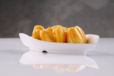 Olgun Jackfruit beyaz desenli tabanlı ve gri arkaplanlı beyaz bir masa takımında güzelce düzenlenmiş..