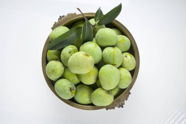 Çiğ mango veya yeşil mango geleneksel pirinç bir kap içinde beyaz desenli arka plan, izole ve üst görünüm