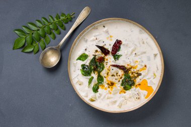 Pachadi ya da Raitha Güney Hindistan mezesi kül koruyucusu, kaymak ve hindistan cevizi kullanarak gri arka planda pirinç bir kaba yerleştirilir.