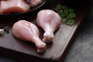 Çiğ tavuk pirzolası, derisiz tavuk pirzolası, tavuk kızartması ve ahşap bir tahtada kişniş yaprağı, sarımsak karanfili ve biber karışımı gri desenli özenle seçilmiş özenle seçilmiş.