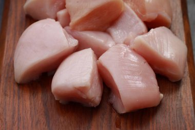 Çiğ tavuk kızartması ahşap tahtada derisiz kesilmiş ve kişniş yapraklarıyla süslenmiş taş desenli ya da grafit renkli arka planda