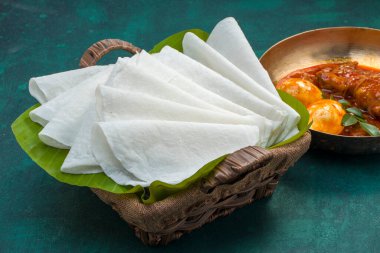 Körili tavuklu güzel Pathiri, pirinç unu kullanılarak yapılan özel malabar yemeği. Muz yaprağına yerleştirilmiş, koyu yeşil desenli bir sepetin içinde beyaz, ince şekilli..