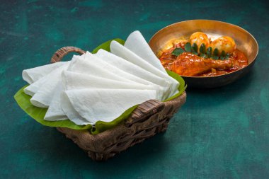Körili tavuklu güzel Pathiri, pirinç unu kullanılarak yapılan özel malabar yemeği. Muz yaprağına yerleştirilmiş, koyu yeşil desenli bir sepetin içinde beyaz, ince şekilli..