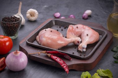 Gri desenli arka planı olan cızırtılı bir cızırtıda dizilmiş taze derisiz tavuk bacakları.. 