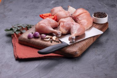 Taze derisiz çiğ tavuk bacakları, bagetler ve çiğ tavuk göğsü kahverengi ahşap bir tabanda gri desenli arka planda..