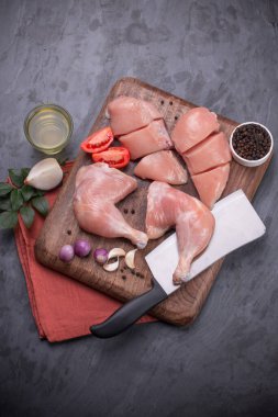 Taze derisiz çiğ tavuk bacakları, bagetler ve çiğ tavuk göğsü kahverengi ahşap bir tabanda gri desenli arka planda..
