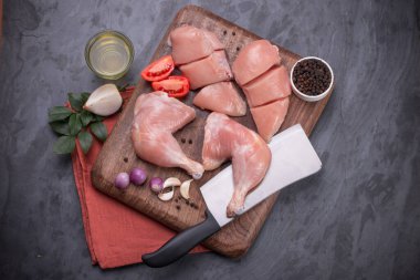 Taze derisiz çiğ tavuk bacakları, bagetler ve çiğ tavuk göğsü kahverengi ahşap bir tabanda gri desenli arka planda..