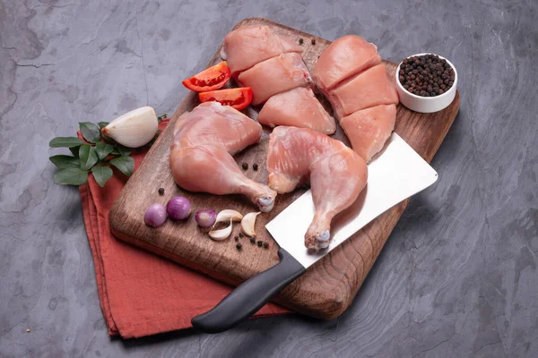 Taze derisiz çiğ tavuk bacakları, bagetler ve çiğ tavuk göğsü kahverengi ahşap bir tabanda gri desenli arka planda..