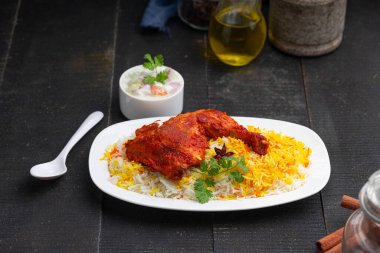 Siyah arkaplan ya da desenli meze olarak tavuk biryani ya da basmathi pilavlı Tandır tavuğu ve raita ya da raitha, seçici odak noktası.