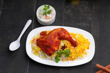 Siyah arkaplan ya da desenli meze olarak tavuk biryani ya da basmathi pilavlı Tandır tavuğu ve raita ya da raitha, seçici odak noktası.