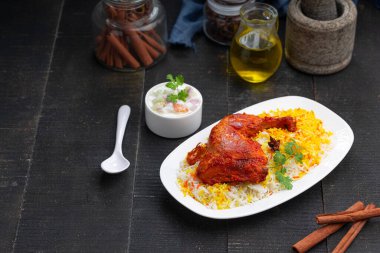 Siyah arkaplan ya da desenli meze olarak tavuk biryani ya da basmathi pilavlı Tandır tavuğu ve raita ya da raitha, seçici odak noktası.