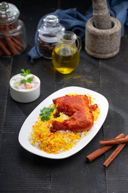 Siyah arkaplan ya da desenli meze olarak tavuk biryani ya da basmathi pilavlı Tandır tavuğu ve raita ya da raitha, seçici odak noktası.