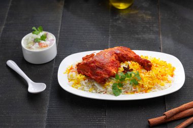 Siyah arkaplan ya da desenli meze olarak tavuk biryani ya da basmathi pilavlı Tandır tavuğu ve raita ya da raitha, seçici odak noktası.