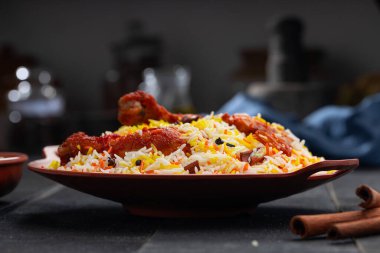 Mandi Biryani tavuğu, Tandır tavuğu, Hydrabadi tavuk biryani basmathi pilavı ve raita ya da raitha ile siyah arkaplan ya da desenli bir toprak takımında servis edilmiş, seçici odak noktası