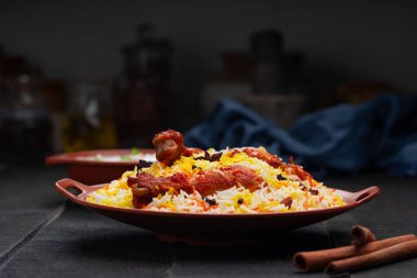 Mandi Biryani tavuğu, Tandır tavuğu, Hydrabadi tavuk biryani basmathi pilavı ve raita ya da raitha ile siyah arkaplan ya da desenli bir toprak takımında servis edilmiş, seçici odak noktası