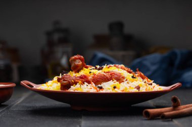 Mandi Biryani tavuğu, Tandır tavuğu, Hydrabadi tavuk biryani basmathi pilavı ve raita ya da raitha ile siyah arkaplan ya da desenli bir toprak takımında servis edilmiş, seçici odak noktası
