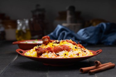 Mandi Biryani tavuğu, Tandır tavuğu, Hydrabadi tavuk biryani basmathi pilavı ve raita ya da raitha ile siyah arkaplan ya da desenli bir toprak takımında servis edilmiş, seçici odak noktası