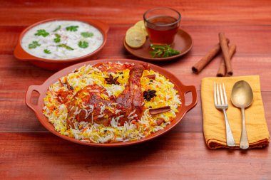 Tavuk dum biryani, Hydrabadi tavuk biryani ile basmathi pilavı ve raita yan yemek olarak ve ahşap arka planda veya dokuda sıcak limon çayı, seçici odak noktası