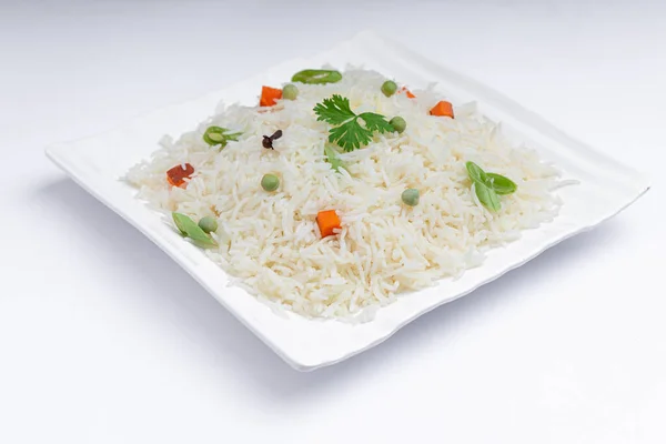 Veg Pulav or Pulao, made using basmathi rice ,vegetables and indian spices. arranged in a square white tableware with white colour background or texture