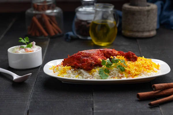 Siyah arkaplan ya da desenli meze olarak tavuk biryani ya da basmathi pilavlı Tandır tavuğu ve raita ya da raitha, seçici odak noktası.