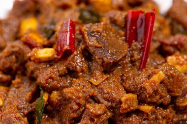 Sığır rostosu ya da pothu ulareyadu, beyaz seramik tabakta ayarlanmış ve gri arkaplanda hindistan cevizi parçalarıyla süslenmiş kerala özel yemeği..