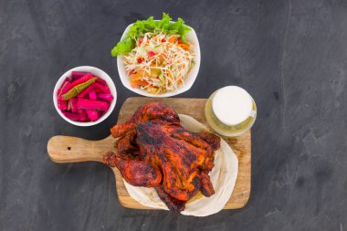 Shawai tavuğu ahşap bir üste, kubular ve gri arka planda mezeler, üst manzara..